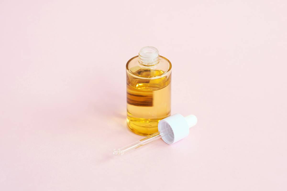 Close-up of hair care serum dropper dispensing product onto palm