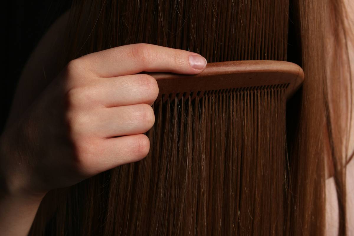 Woman applying anti-frizz serum to damp hair in front of a mirror